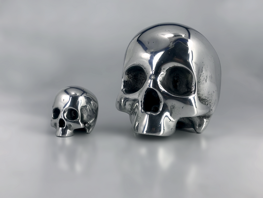 Two solid aluminium skull awards on a reflective surface with a neutral background