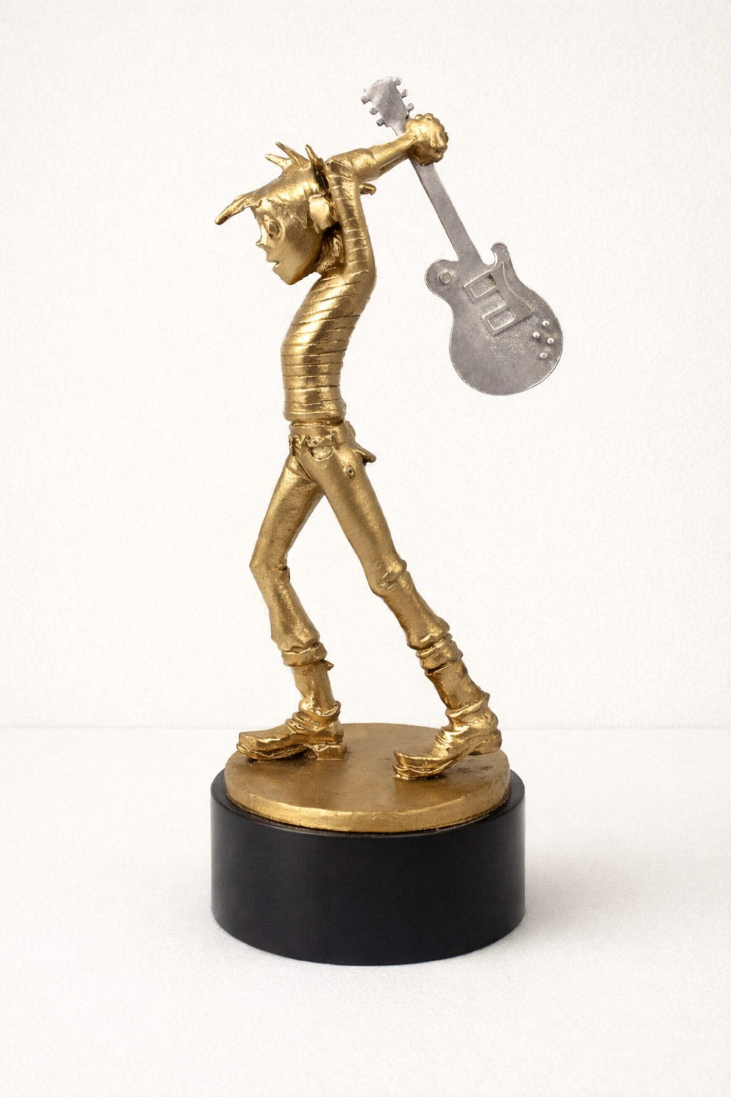 Gold 3D printed award sculpture of a teenage cancer trust kid playing a guitar on a black base against a white background