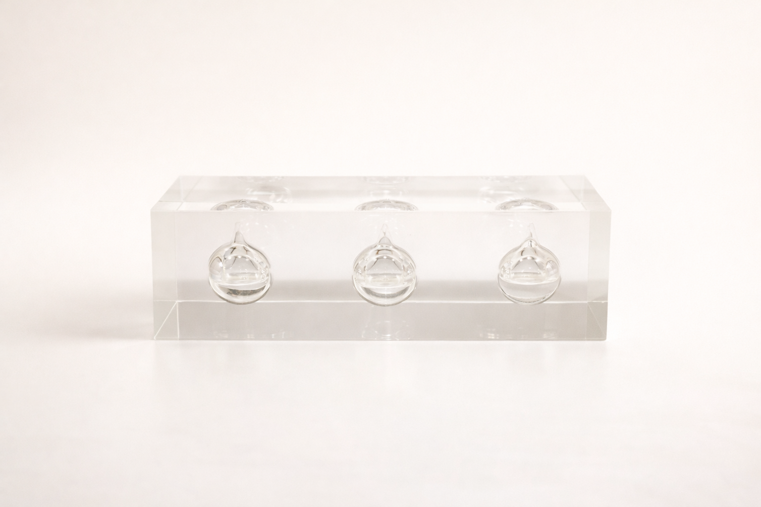 Clear acrylic award with three small round oil inserts on a white background