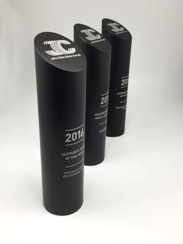 Three black cylindrical awards with text on a white background