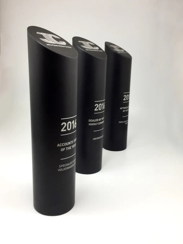 Three black cylindrical awards with text on a white background