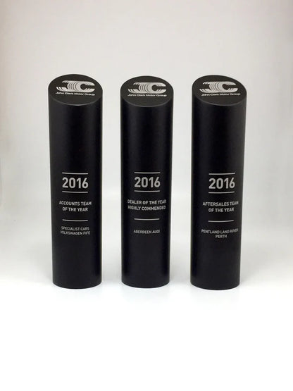Three black cylindrical awards with '2016' and text on a white background