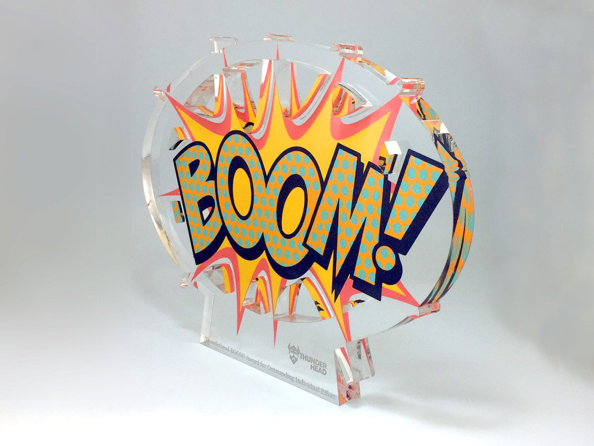 Decorative award with 'BOOM!' text on a clear stand against a white background