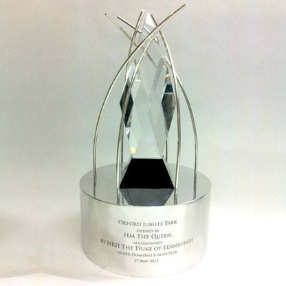 Silver and cut glass trophy with engraved text on a white background