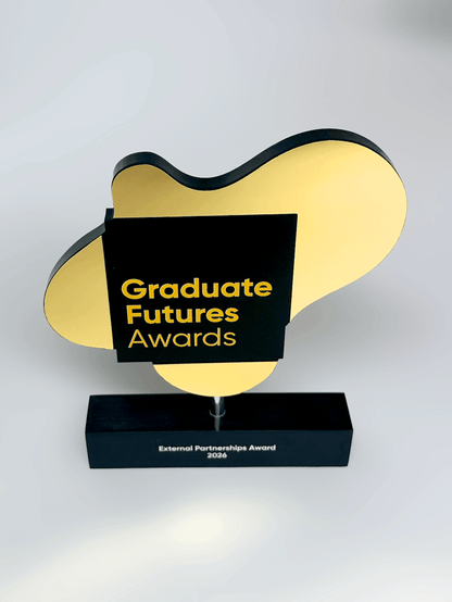 An award trophy with a black and gold abstract cloud-like plaque on a black rectangular base. The front plaque reads 'Graduate Futures Awards' in gold text, and the base reads 'External Partnerships Award 2025'.