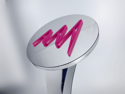 Close-up of pink Perspex "AMA" lettering set into the polished mirror aluminium disc of the Pink Flash Award