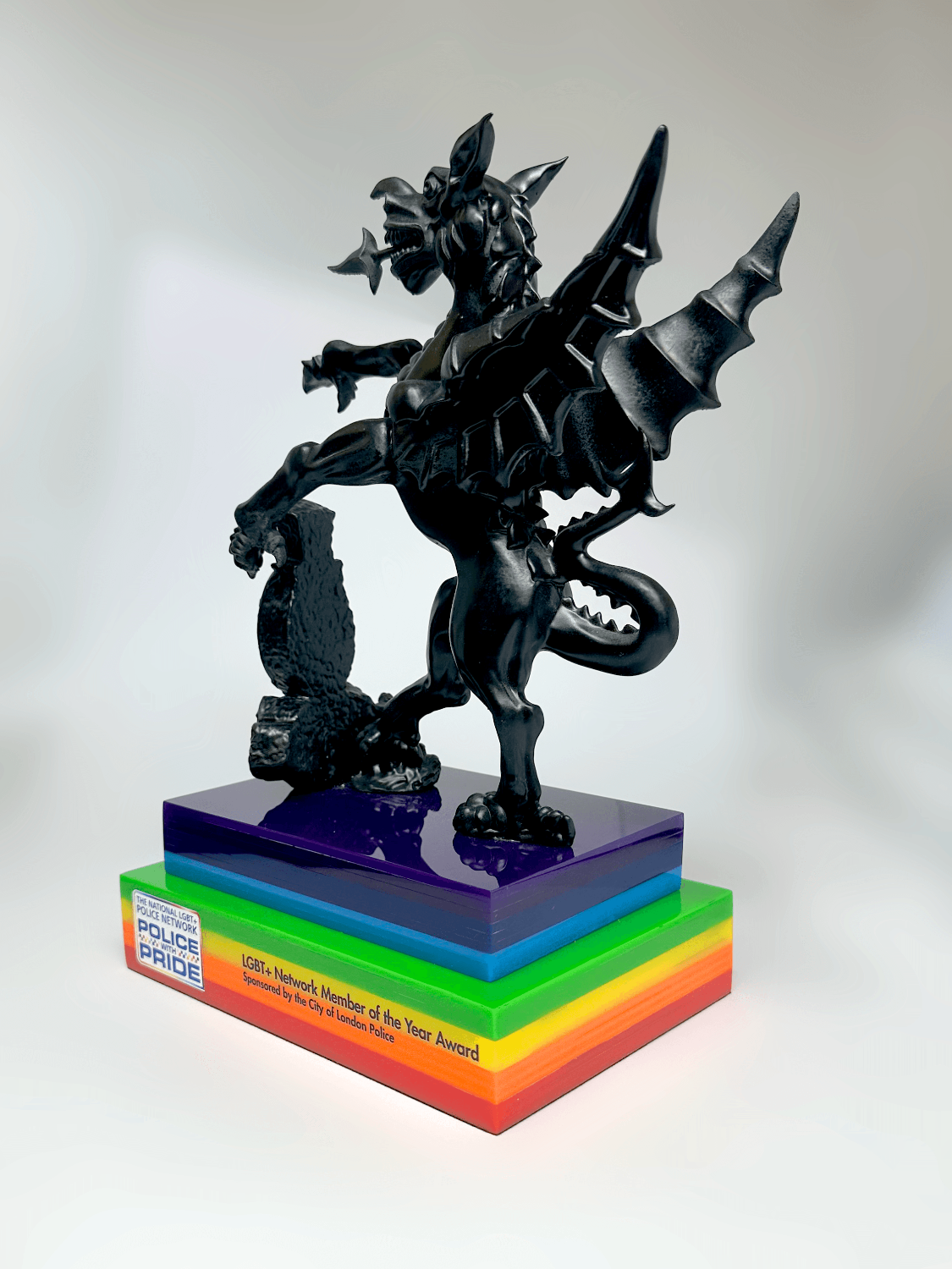 Side view of bespoke griffin trophy, matte black resin sculpture on laminated rainbow acrylic plinth