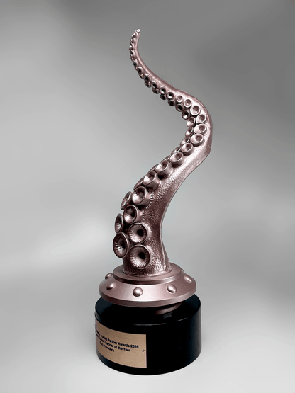 A side shot of an octopus tentacle award sculpture with metallic rose-gold suction cups and a black cylindrical base, photographed on a smooth gray studio background.