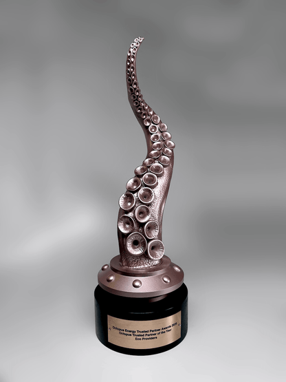 An octopus tentacle award sculpture with realistic suction cups, mounted on a metallic bronze base and a round black pedestal with a gold nameplate, photographed against a neutral gray gradient background.
