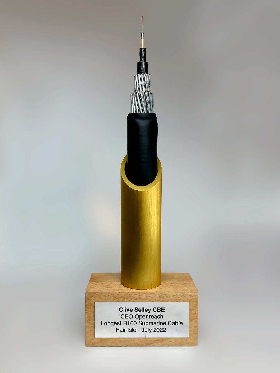 Model of a submarine cable award on a wooden base with a gray background