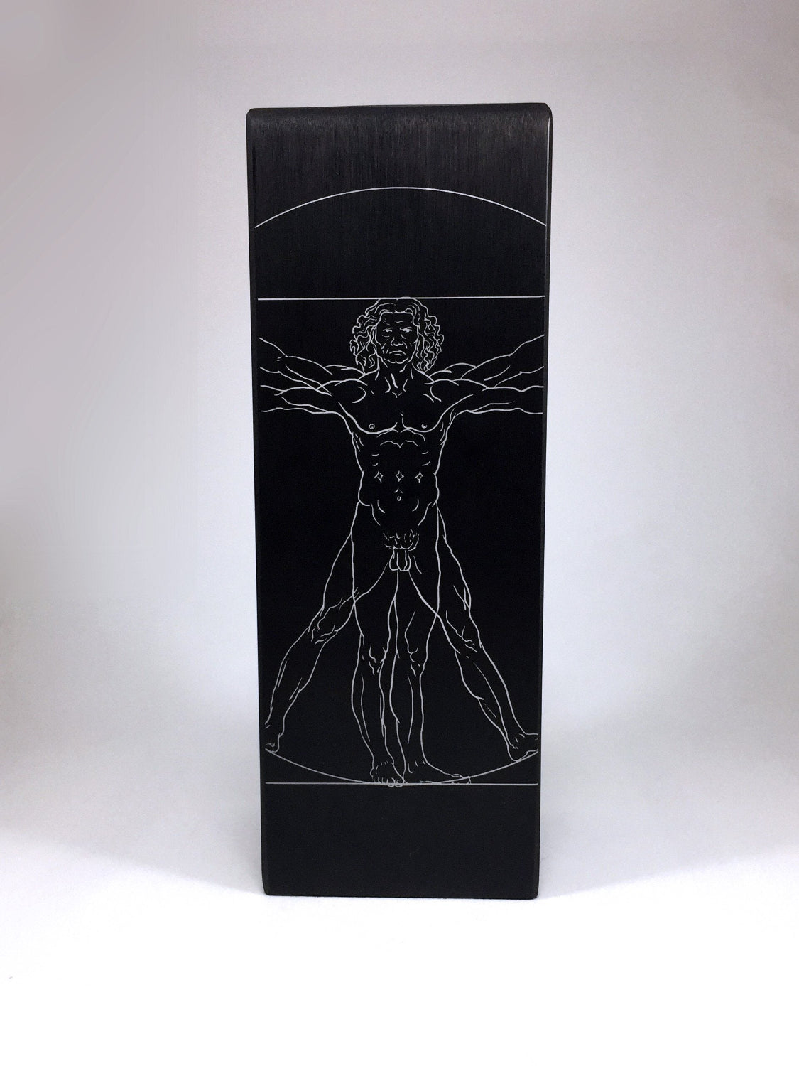 Black rectangular metal award with a vitruvian man line drawing etched into the award.