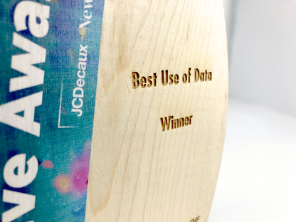 Wooden award with 'Best Use of Data Winner' text and JCDecaux branding.